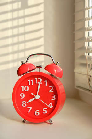 Red alarm clock early morning windowsill in rays sunの写真素材