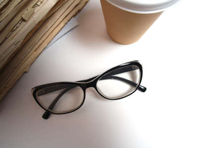 Stack old newspapers, glass of coffee and glasses for reading newspaper newsの写真素材