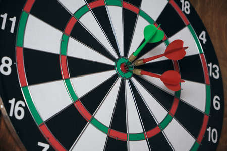 Concept of competition and goal achievement. Achieving goals in business and life. Dartboard with three darts stuck right center of targetの写真素材
