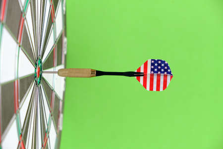 Concept goal achieving.Achieving goals in business, politics and life. Dartboard with darts painted with American flag stuck right into target.On green backgroundの写真素材