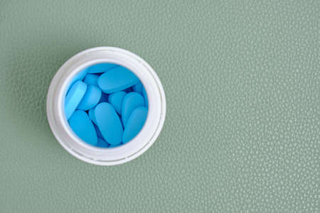 An open bottle with pills on a green background