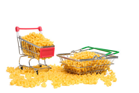 Cart and shopping basket with pasta in the middle of scattered pasta on a white backgroundの写真素材