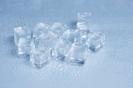 Ice cubes are covered with water droplets on light blue background