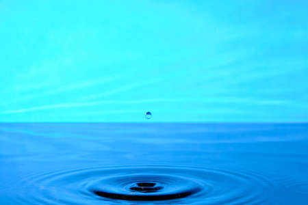 Splash water after drop falls.Blue abstract background with drop in waterの写真素材