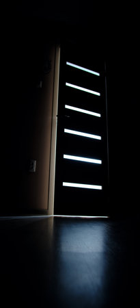 Light breaks through glass and the crack half open door into the dark bedroomの写真素材