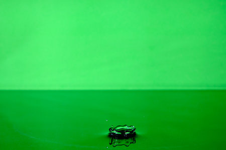 Splash water after drop falls.Green abstract background with drop in waterの写真素材