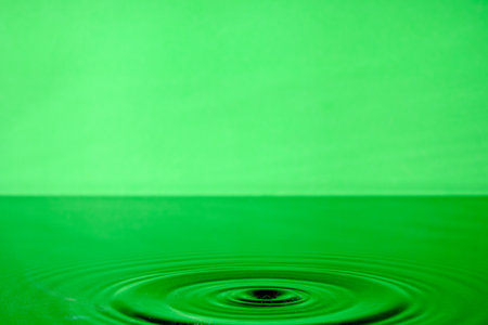 Bright green background with diverging circles from dropped drop on surface waterの写真素材