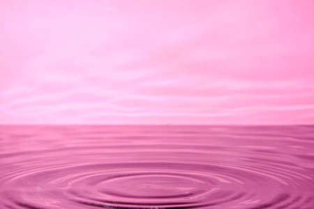 Bright pink background with diverging circles from dropped drop on surface waterの写真素材