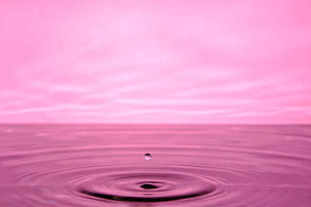 Splash water after drop falls.Pink abstract background with drop in waterの写真素材