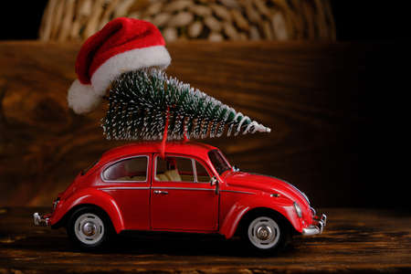 Kostanay, Kazakhstan 2022.Red toy car on wooden background with spruce on roof, Christmas decorations,の写真素材