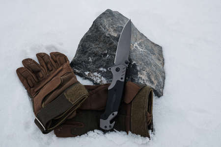 Tactical gloves and a folding knife in the snowの写真素材