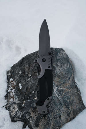 Camping folding knife lies on a stone in winter.Active recreation hiking and travelingの写真素材