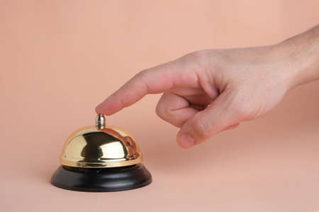 Pressing your finger on hotel service call button on pastel beige background.Conceptual hotel, travel and recreationの写真素材