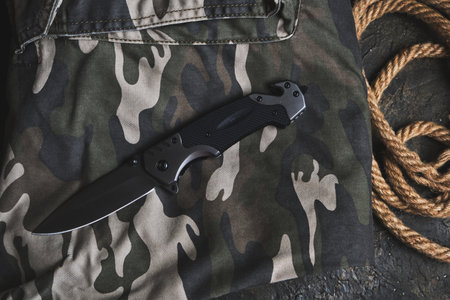 Tactical folding knife for survival and rope on camouflage military clothingの写真素材