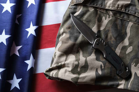 Folding tactical knife and military camouflage clothing on background American flagの写真素材