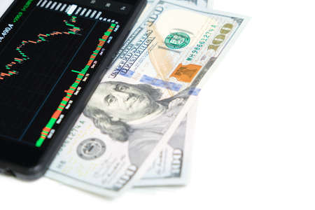 Stock exchange chart on smartphone screen and hundred dollar bills on white background.Concept,shares, business and financeの写真素材
