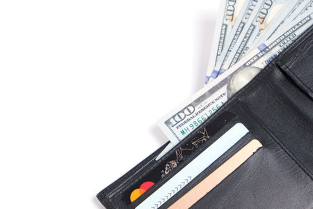 Black leather wallet with stack hundred dollar bills and bank cards on white background.Concept wealth and affluenceの写真素材