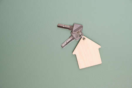 Keychain in form house with keys green background.Concept buying house, apartment or rent