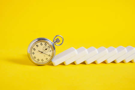 Stopwatch and scattered dominoes on a yellow background. times upの写真素材