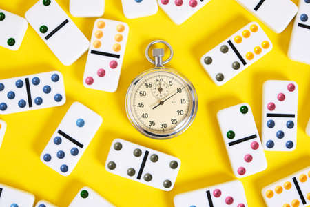 Stopwatch and scattered dominoes on a yellow background. times upの写真素材