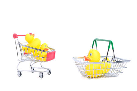 Yellow rubber ducks in shopping cart on a white background.Children goods and purchasesの写真素材