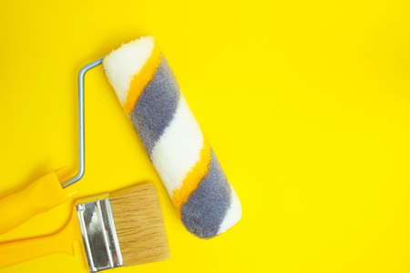 Paint roller and brush for painting and repairing walls on yellow background