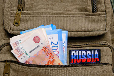 Paper banknotes Russian ruble in denominations two and five thousand pocket backpack with inscription Russiaの写真素材