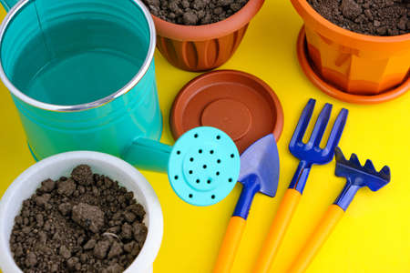 Flower pots, watering can and garden tool bright yellow backgroundの写真素材