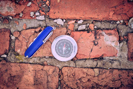 Penknife, compass on the background of old brick masonry, urban styleの写真素材