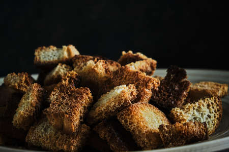 Wooden plate with fried breadcrumbs dark background. Rustic setting and foodの写真素材