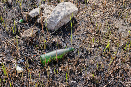 Garbage and glass bottles on the scorched earth after the fire