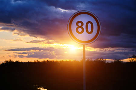 Speed limit sign of 80 km h background bright sunset and cloudsの写真素材