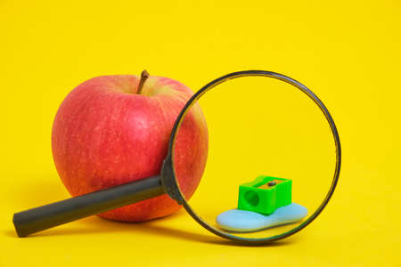 Apple magnifier and sharpener with eraser yellow background.Preparation for schoolの写真素材