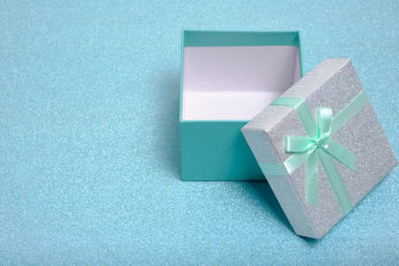 Open gift box with turquoise ribbon and bow on shiny backgroundの写真素材