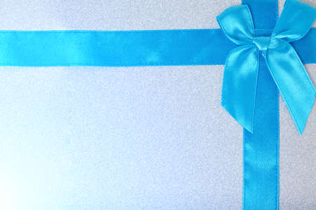 Blue ribbon tied with bow on a shiny gift boxの写真素材