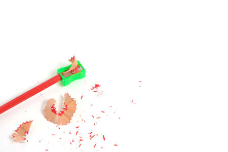 Sharpener and sharpened red pencil with sawdust on white background