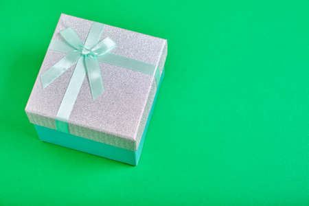 Gift box green background is tied with turquoise ribbon with bow