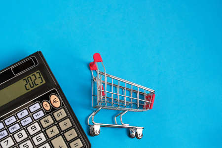 Calculator and shopping cart on blue background.Concept of shopping and grocery shopping