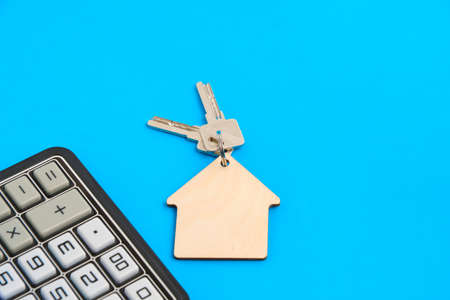 Calculator and keychain with house keys blue background.Concept mortgages, buying and renting housingの写真素材