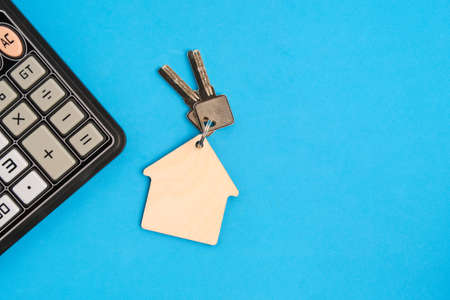 Calculator and keychain with house keys blue background.Concept mortgages, buying and renting housingの写真素材