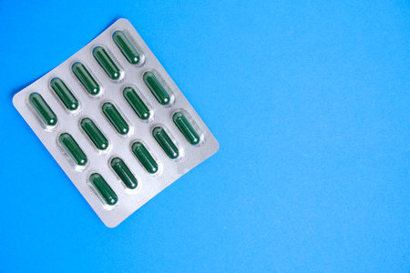 Green pills in package blue backgroundの写真素材