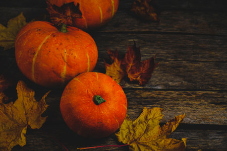 Pumpkins and fallen autumn foliage wooden backgroundの写真素材
