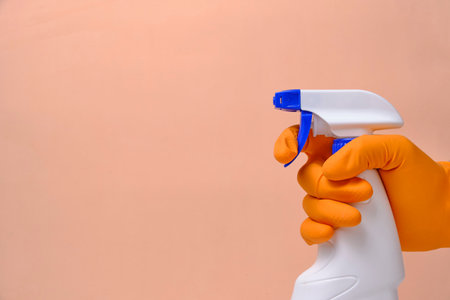 Sprayer for cleaning windows and plumbing in hand with glove on beige backgroundの写真素材