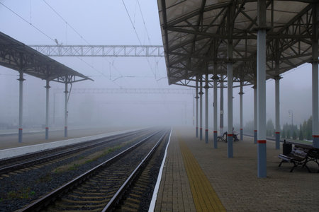 Empty platform at station and rails going into fog