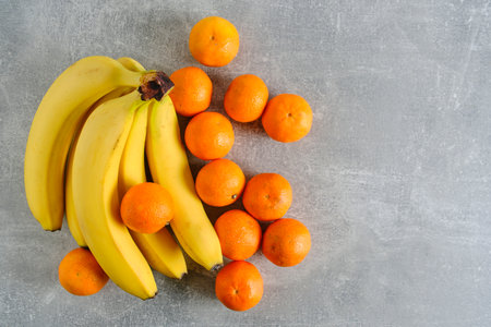 Bunch ripe, yellow bananas and tangerines gray concrete backgroundの写真素材