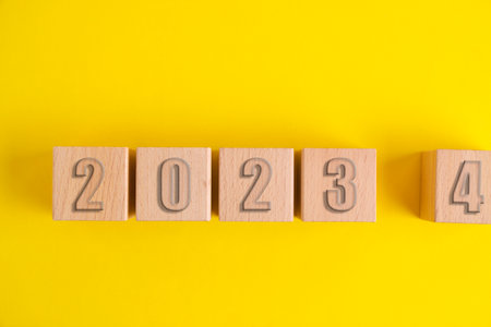 Wooden cubes with numbers 2023 yellow background turning into 2024