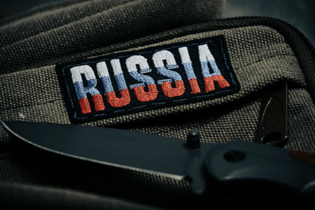 Folding knife and khaki backpack with patch with inscription Russia