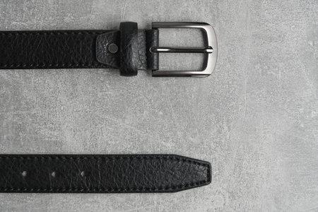 Black men leather belt with metal badge gray concrete backgroundの写真素材