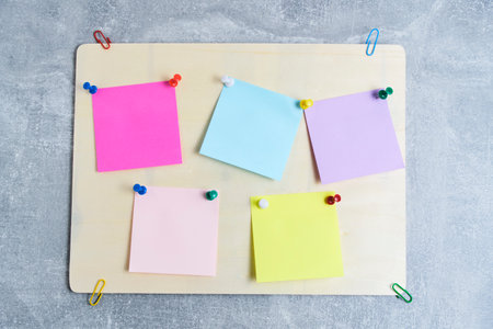 Plywood board is pasted with multicolored stickers for writing notes concrete backgroundの写真素材
