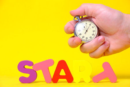 Word start is laid out multicolored letters, hand holds stopwatch